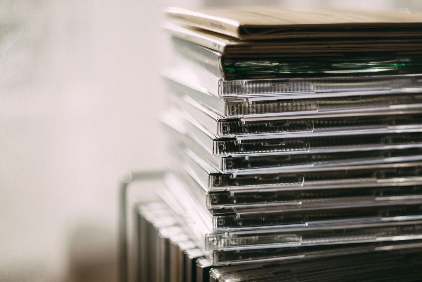 A stack of CD jewel cases arranged beside a shelf.