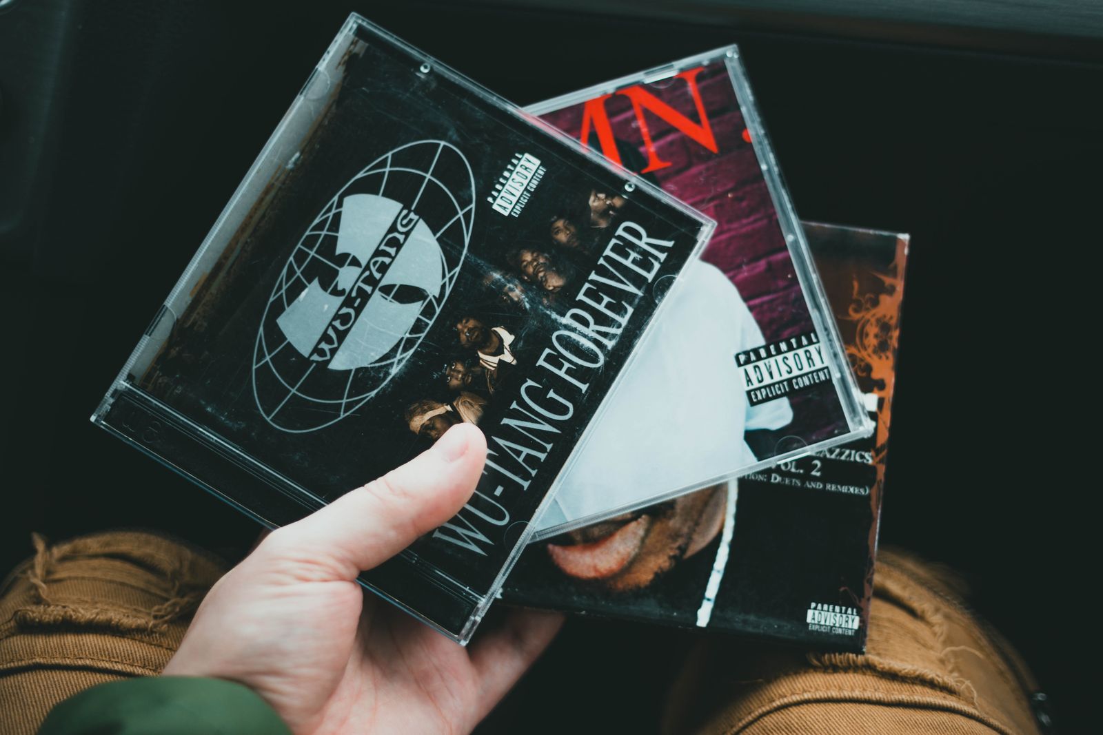 A music collector holding several CDs in jewel cases.